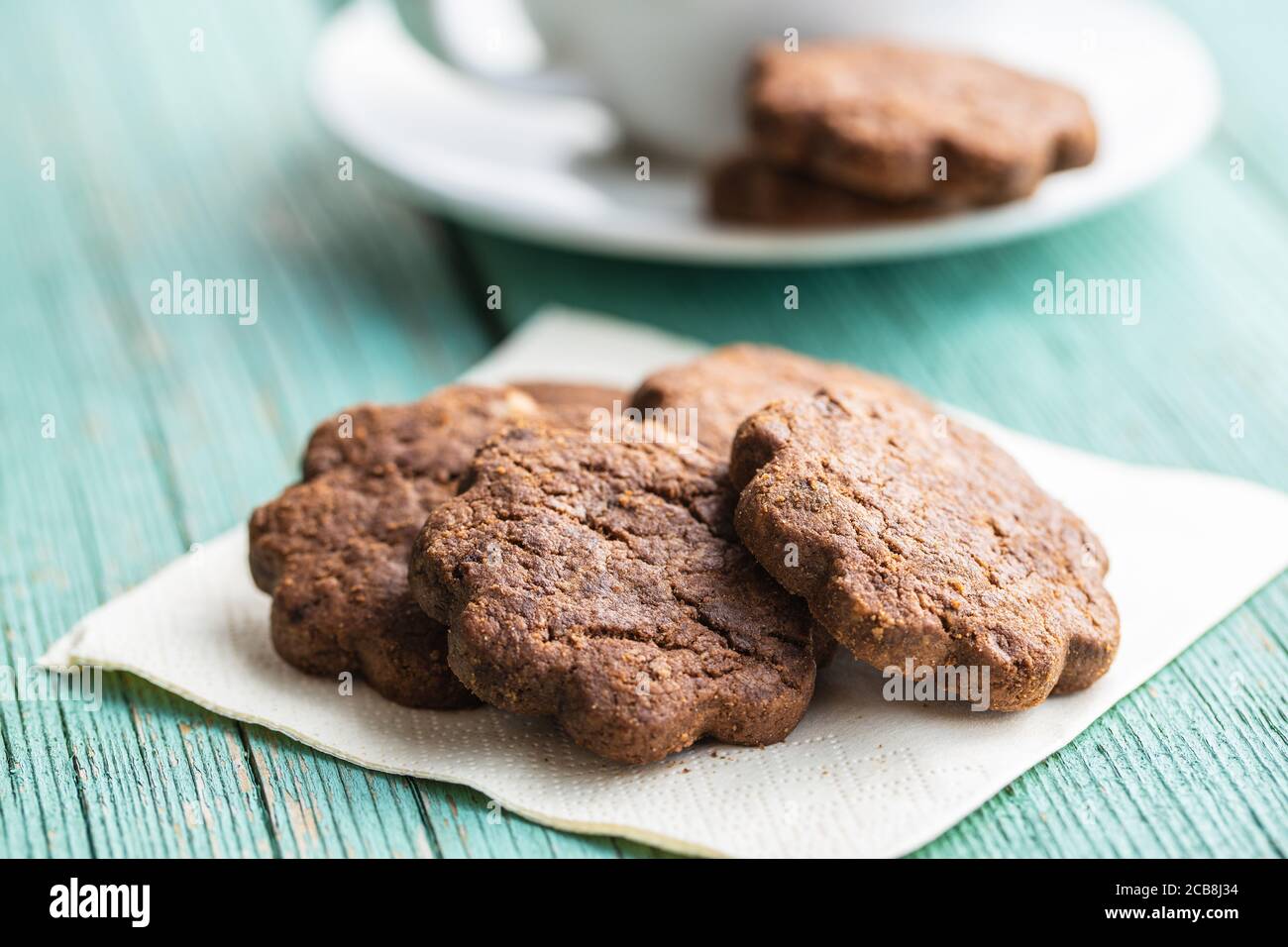 Biscotti dolci. Croccanti biscotti al cioccolato forma fiore su tavola di legno verde. Foto Stock