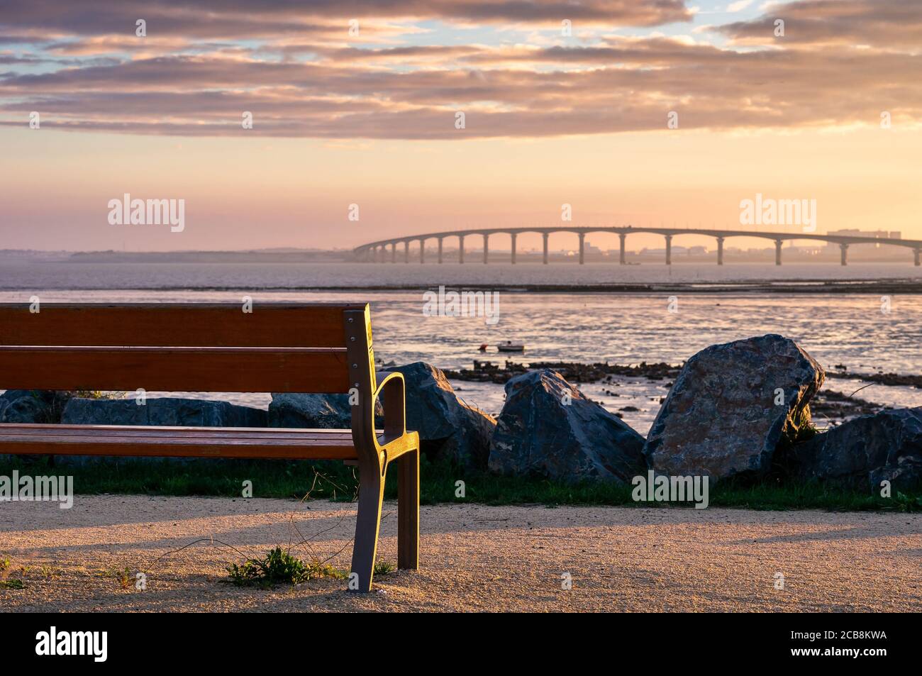 una panchina con nessuno sul primo piano con ponte Di isola di Re sullo sfondo Foto Stock