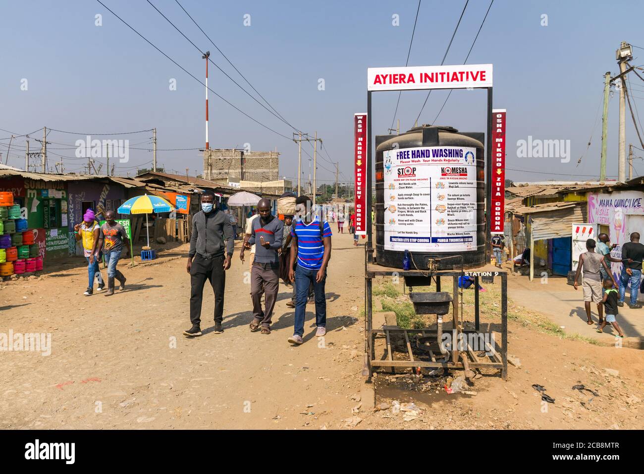Un grande serbatoio d'acqua di plastica con un cartello di lavaggio a mano libera su di esso per combattere il coronavirus dal lato di una strada sterrata, Nairobi, Kenya Foto Stock
