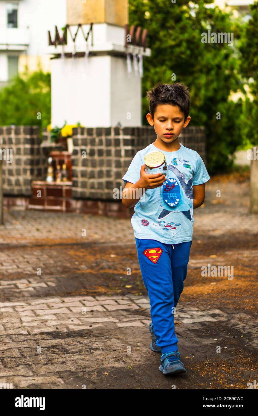 POZNAN, POLONIA - 20 luglio 2020: Ragazzo caucasico polacco di sei anni che cammina su una strada tenendo un vaso di vetro con insetti Foto Stock