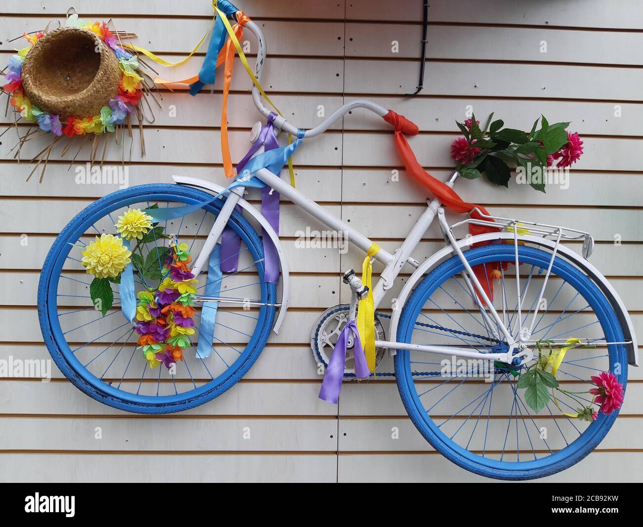 Primo piano di una bicicletta colorata appesa a una bianca parete Foto Stock