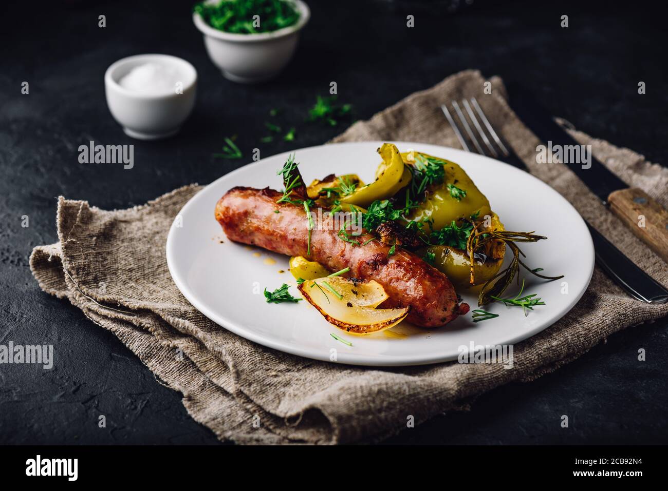 Salsiccia di maiale al forno con peperoni verdi, cipolla ed erbe Foto Stock