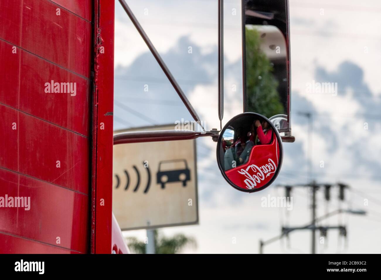 Immagine del logo aziendale della Coca cola. Riflessa nello specchio retrovisore di un camion di consegna. Scena urbana Foto Stock