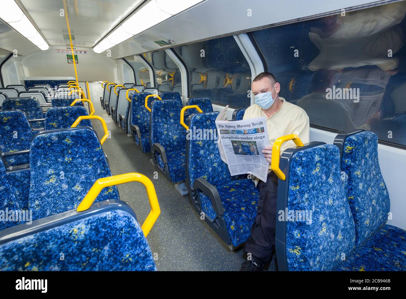 Un uomo solista su un treno vuoto legge le notizie di Coronavirus dal quotidiano Sydney Morning Herald di Sydney, Australia, mentre la popolazione abbandona i luoghi pubblici in previsione di un blocco a livello di città. Molte aziende e luoghi di ritrovo classificati dal governo come non essenziali - come pub, ristoranti, spiagge e luoghi di culto - sono stati considerati off-limits fino a nuovo avviso. (Modello rilasciato) Foto Stock