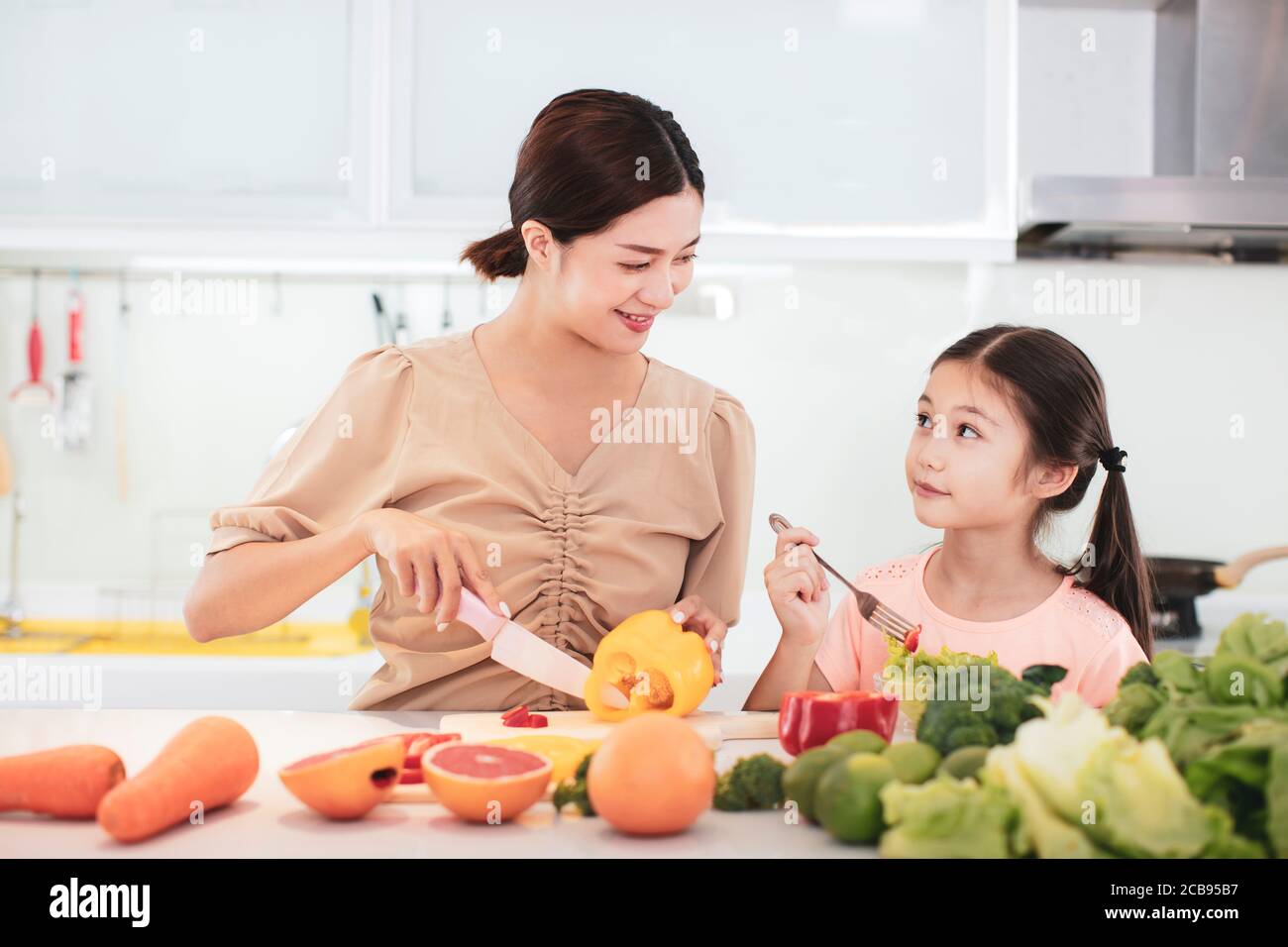 Felice Madre e figlia del bambino che mangia le verdure e la frutta Foto Stock