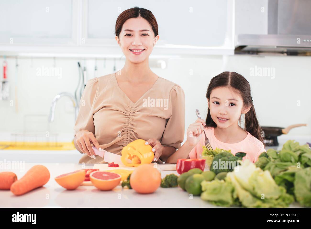 Felice madre e figlia bambino che preparano le verdure e la frutta Foto Stock