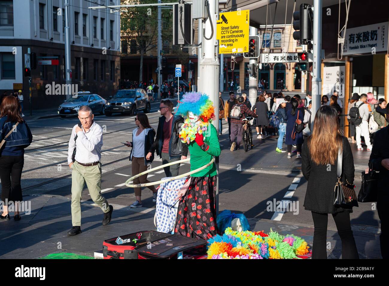 26.09.2019, Sydney, nuovo Galles del Sud, Australia - la gente attraversa un passaggio pedonale nel sobborgo di Haymarket a Chinatown vicino ad un artista di strada. Foto Stock