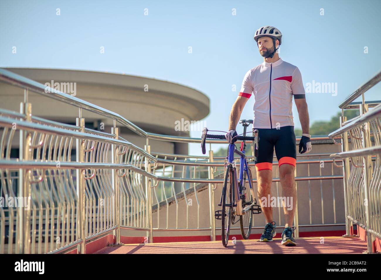 Alto ciclista maschile a piedi con biciclette all'aperto Foto Stock
