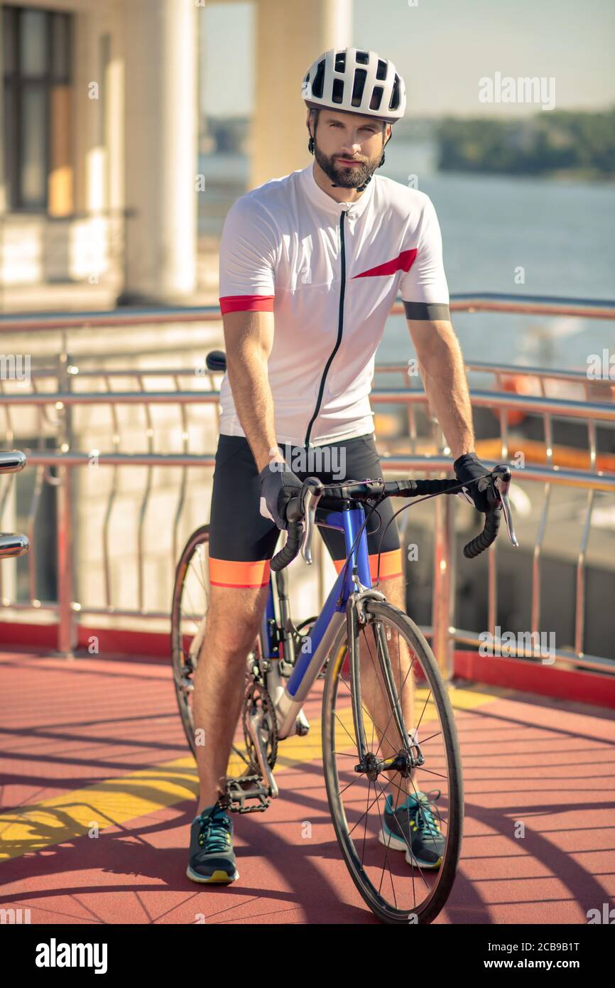 Uomo serio in abbigliamento sportivo e casco in bicicletta Foto Stock