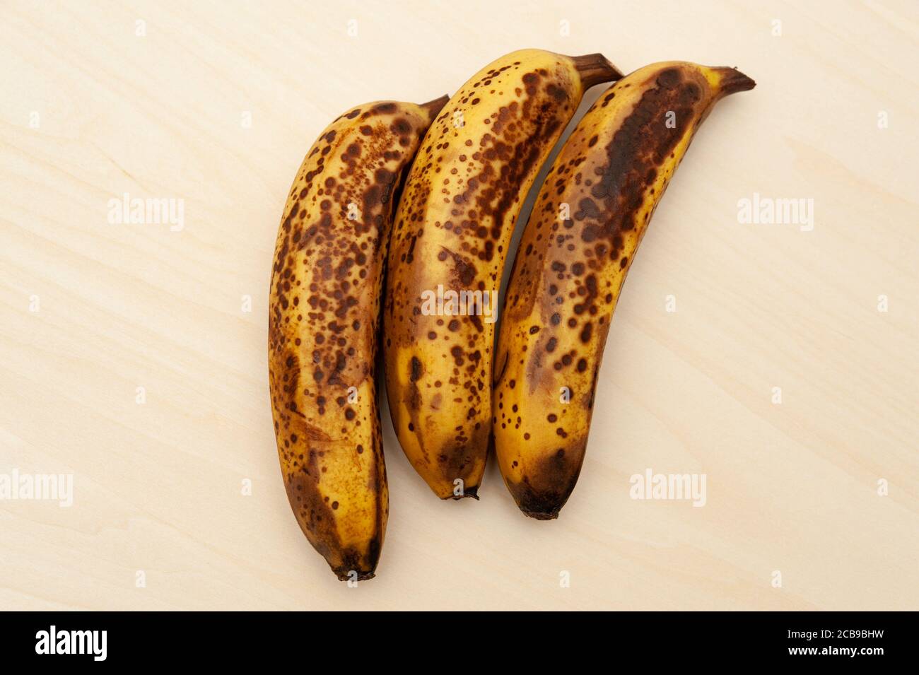 Tre banane mature isolate su sfondo di legno chiaro. Vista dall'alto. Spazio di copia. Foto Stock
