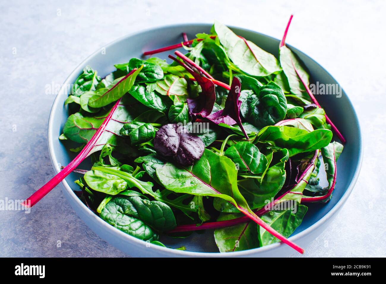 mescolare le foglie di insalata fresca in una ciotola blu vista dall'alto Foto Stock