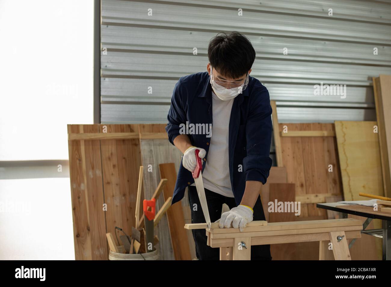 Asian man Carpenter che lavora con disegno tecnico o carta da costruzione di progetto che giace su un laboratorio con attrezzi di Falegnameria e legno nel paese Foto Stock