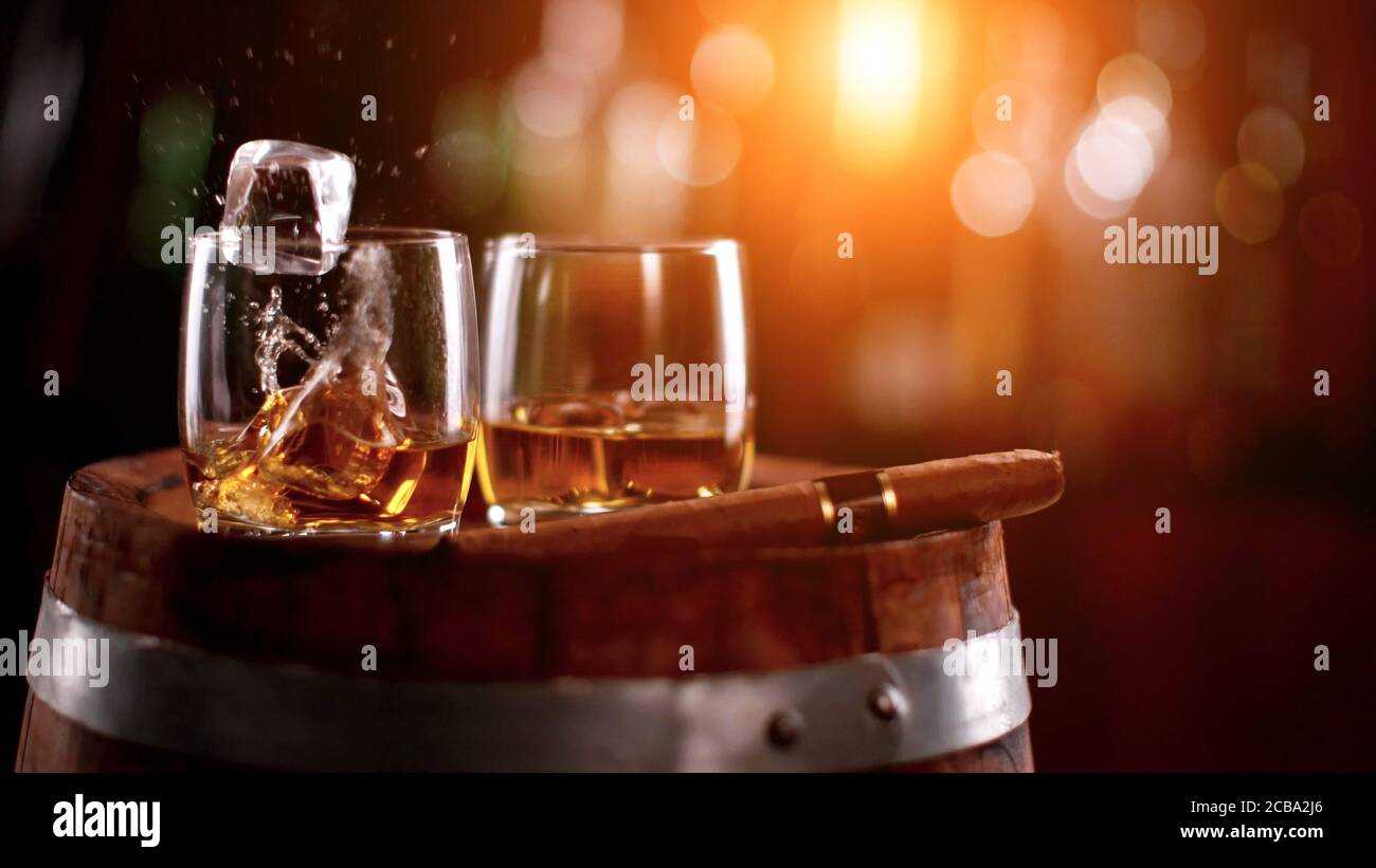 Whisky bevande con rocce di ghiaccio volanti. Posto su fusto di legno. Bassa profondità di messa a fuoco Foto Stock