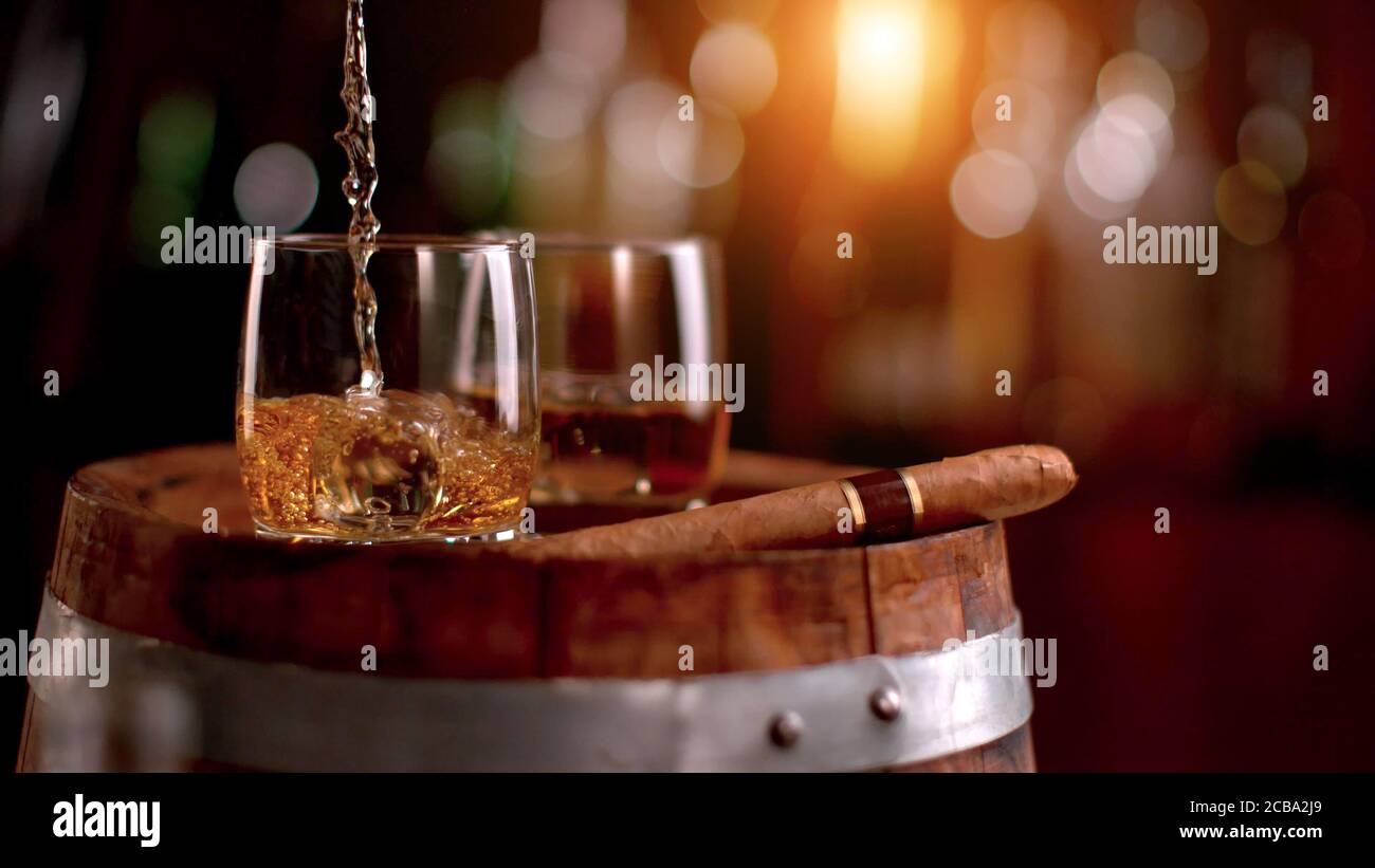 Versare il whisky nel bicchiere. Posto su fusto di legno. Bassa profondità di messa a fuoco Foto Stock