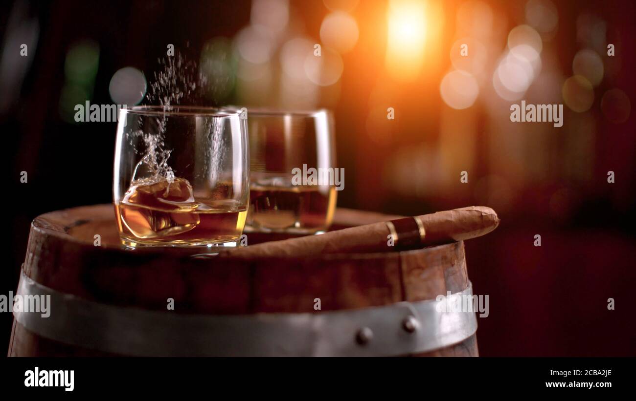 Whisky bevande con rocce di ghiaccio volanti. Posto su fusto di legno. Bassa profondità di messa a fuoco Foto Stock