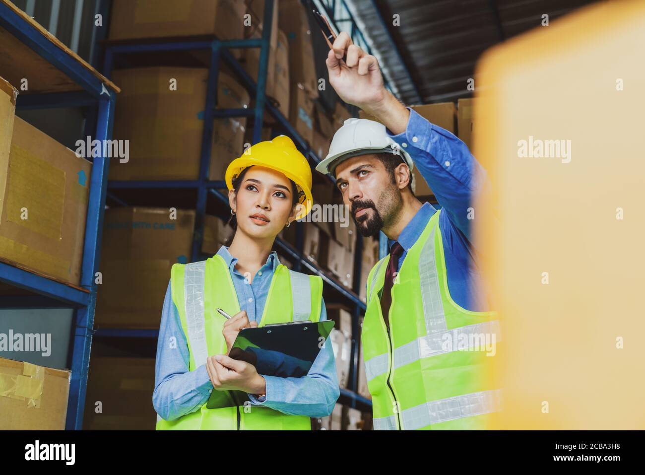 Responsabile del lavoratore di magazzino assegna e comanda in serio sguardo ad assistente responsabile donna in magazzino locale o fabbrica, asiatico e bianco caucasico pisello Foto Stock Responsabile del lavoratore di magazzino assegna e comanda in serio sguardo ad assistente responsabile donna in magazzino locale o fabbrica, asiatico e bianco caucasico pisello Foto Stock