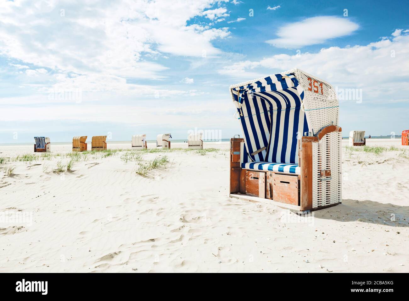 Sedia o panca in vimini di legno a strisce blu e bianche una spiaggia tropicale di sabbia bianca in caldo sole estivo un concetto di viaggio e vacanza Foto Stock