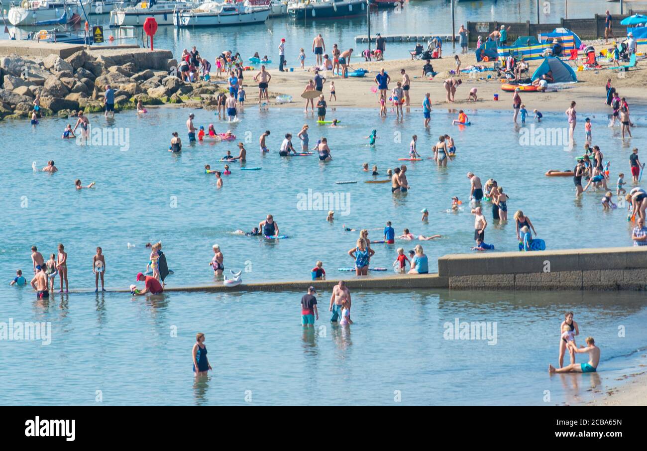 Lyme Regis, Dorset, Regno Unito. 12 agosto 2020. Regno Unito Meteo: I vacanzieri, le famiglie e i bagnanti si sono inzuppati nel sole caldo bruciante alla stazione balneare di Lyme Regis come le temperature record di rottura salgono di nuovo. Il calore sulla spiaggia era già intenso alle 10.30. Credit: Celia McMahon/Alamy Live News Foto Stock