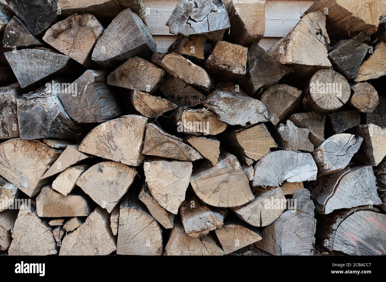foto full-frame di pila di legna da ardere, billette di legno su fondo muro di legno Foto Stock