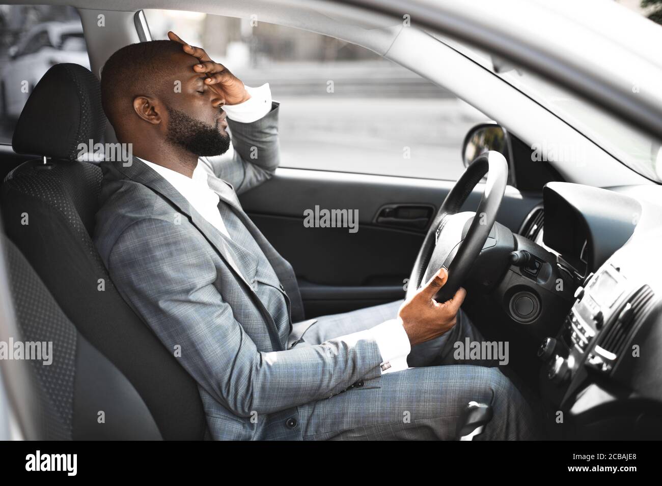 Imprenditore africano esausto sulla strada di casa, guida auto Foto Stock
