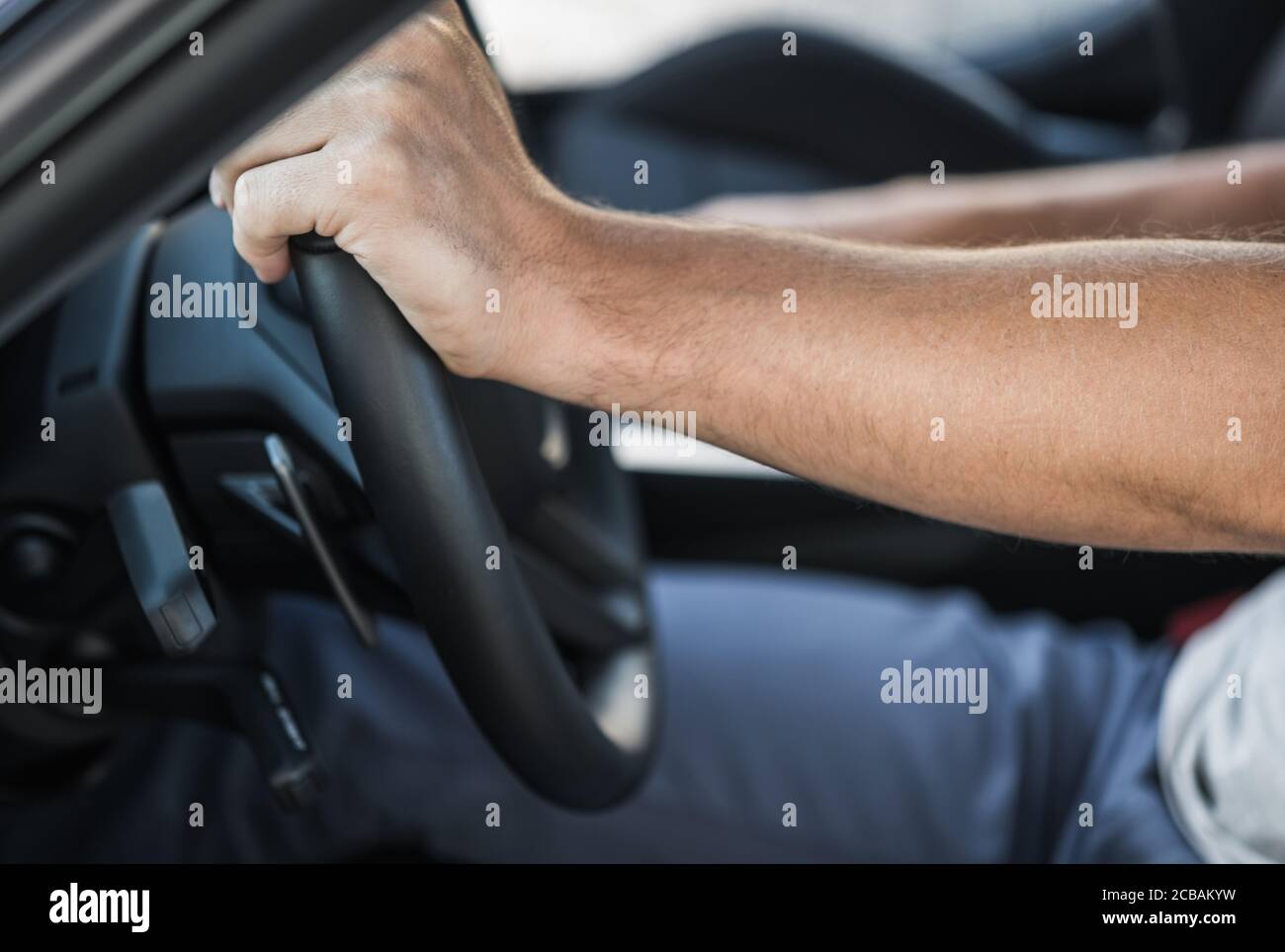 Il conducente caucasico ha le mani sul volante della vettura in primo piano. Tema industria automobilistica. Foto Stock
