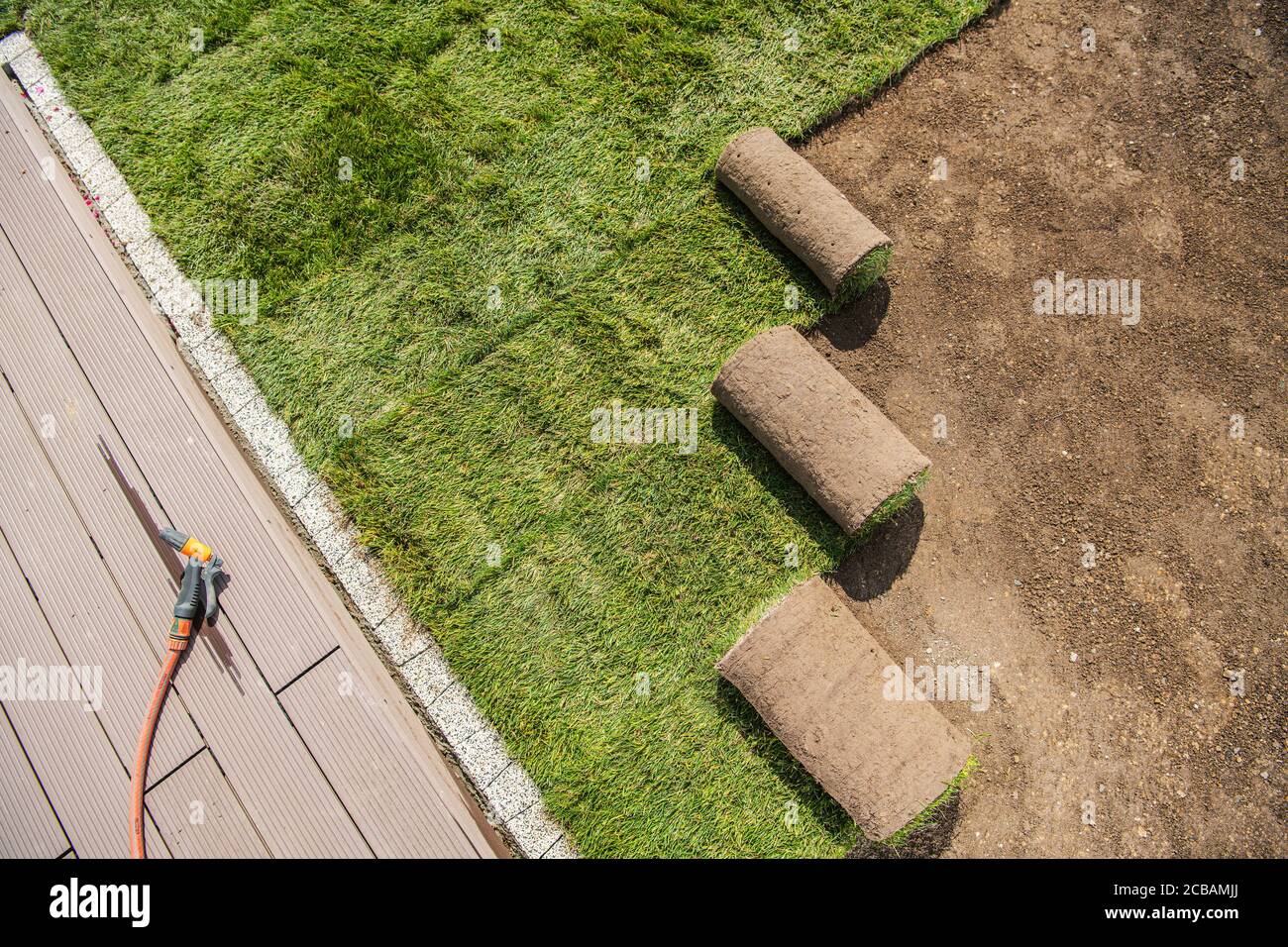 Settore paesaggistico. Rotoli di erba turfs appena installati accanto alla terrazza della piscina. Tema industriale. Foto Stock
