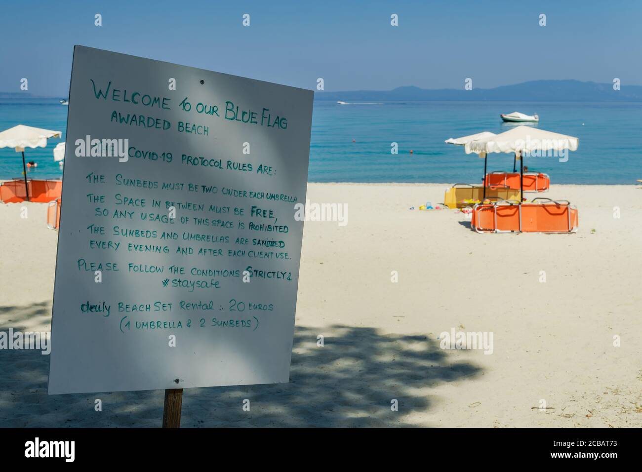 CHALKIDIKI, Grecia Covid-19 segno precauzioni spiaggia. Informazioni a spiaggia vuota, che descrivono le regole del protocollo per lettini e ombrelloni, per proteggere dal virus. Foto Stock