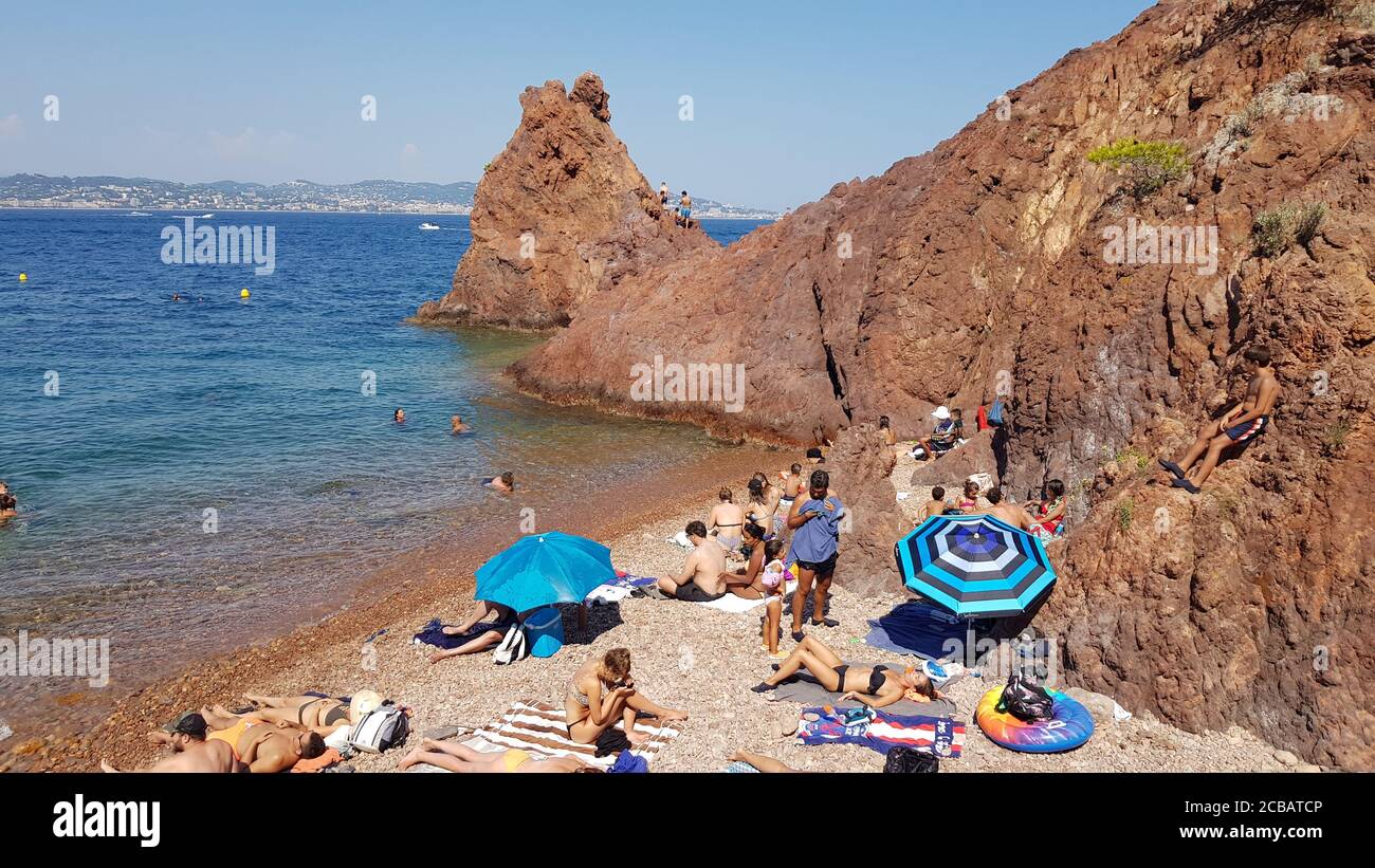 Theoule sur Mer, Francia - 09 agosto 2020: Persone che godono il bel tempo in spiaggia. La zona di Esterel è famosa per i suoi paesaggi con rocce rosse Foto Stock
