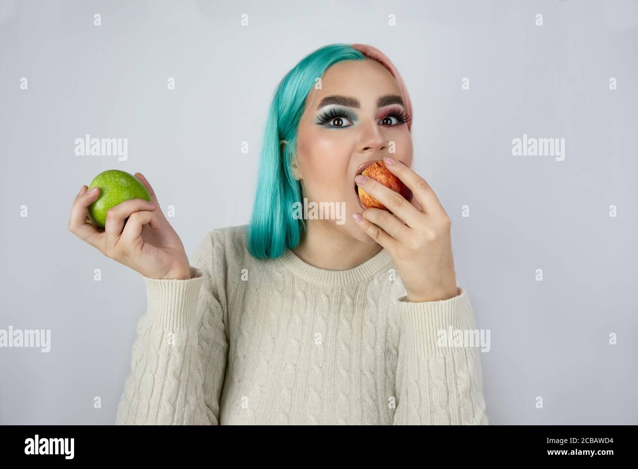 giovani donne con capelli tinti nei colori blu e rosa e tenendo mele verdi e rosse Foto Stock