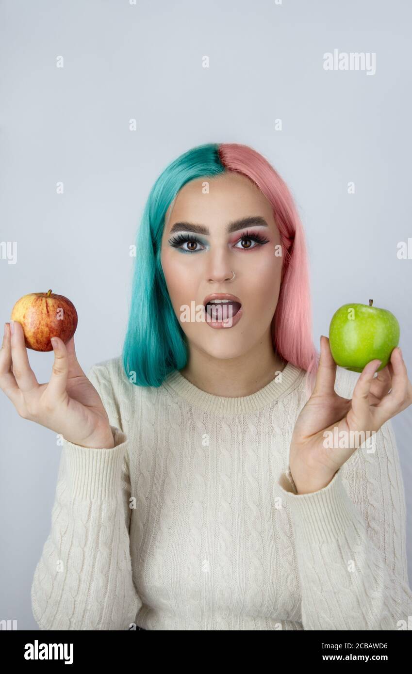 giovani donne con capelli tinti nei colori blu e rosa e tenendo mele verdi e rosse Foto Stock