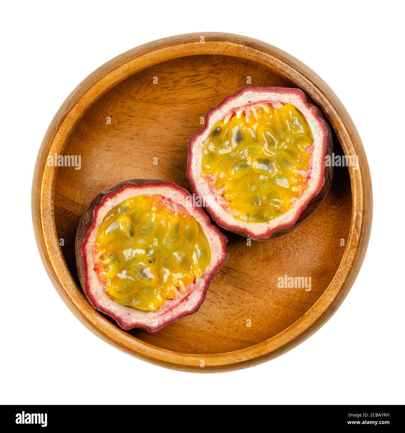 Frutta fresca di passione tagliata in due metà, in ciotola di legno. Frutti con pelle viola e polpa gialla con molti semi. Può essere mangiato crudo. Foto Stock