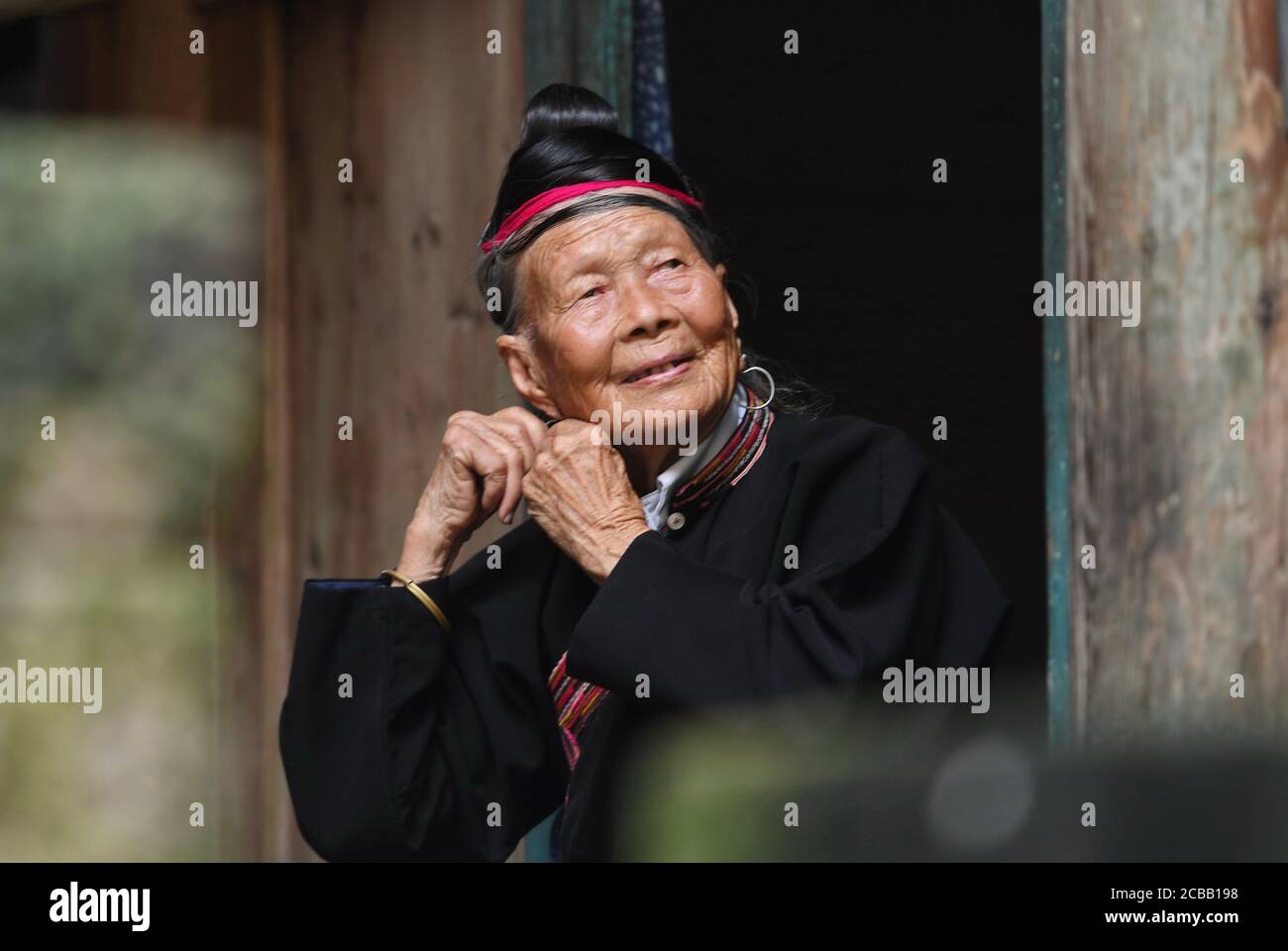 (200812) -- NINGDE, 12 agosto 2020 (Xinhua) -- Zhong Lianjiao organizza i costumi a casa al villaggio Banyueli nella contea di Xiapu, nella provincia del Fujian della Cina sudorientale, 5 agosto 2020. È comune vedere Zhong Lianjiao, una donna di 89 anni del gruppo etnico sempre in costumi tradizionali lei, introdurre le culture del suo gruppo etnico ai turisti che visitano l'antico villaggio di Banyueli. Vive nel villaggio per decenni, Zhong si è adoperata per promuovere il turismo del villaggio introducendo le culture locali ai turisti. Banyueli è un villaggio dove reliquie culturali e costumi popolari di lei Foto Stock