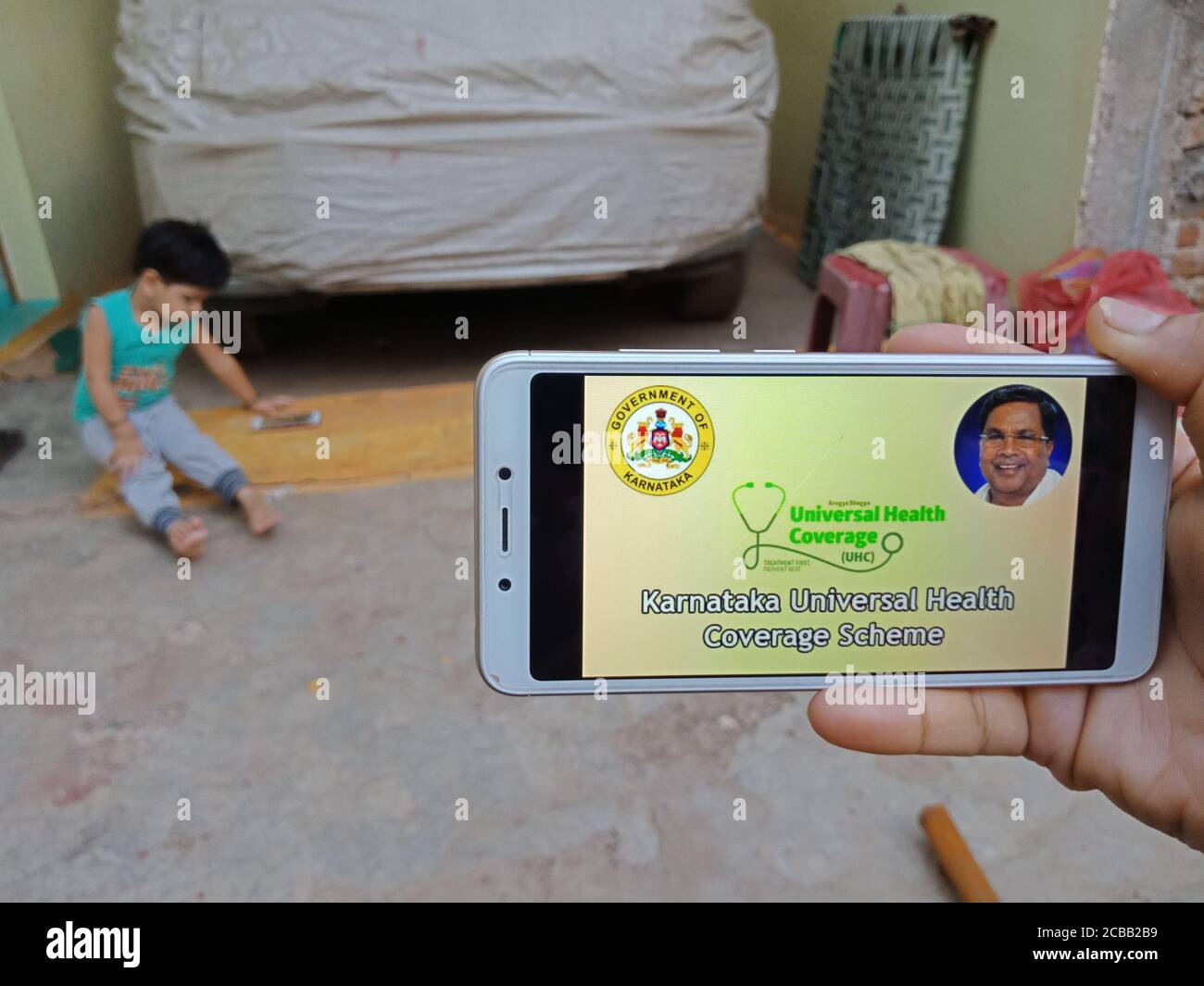 DISTRETTO KATNI, INDIA - 28 MAGGIO 2020: Una signora indiana che tiene uno smartphone con visualizzazione Karnataka schema di copertura sanitaria universale su schermo, moderno e. Foto Stock