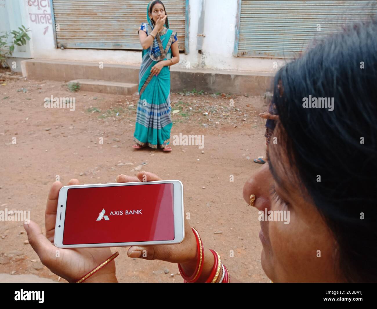 DISTRETTO KATNI, INDIA - 02 GIUGNO 2020: Una donna indiana che tiene lo smartphone con l'esposizione del logo della società di banca di asse sullo schermo, e moderno di banca Foto Stock
