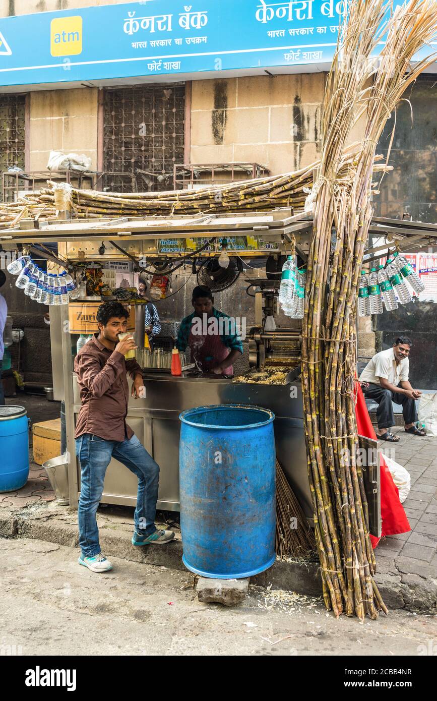 Mumbai, India - 22 novembre 2019: L'uomo locale inideale beve succo di canna da zucchero sulla strada a Mumbai, India. Mumbai è famosa per il suo cibo di strada. Foto Stock