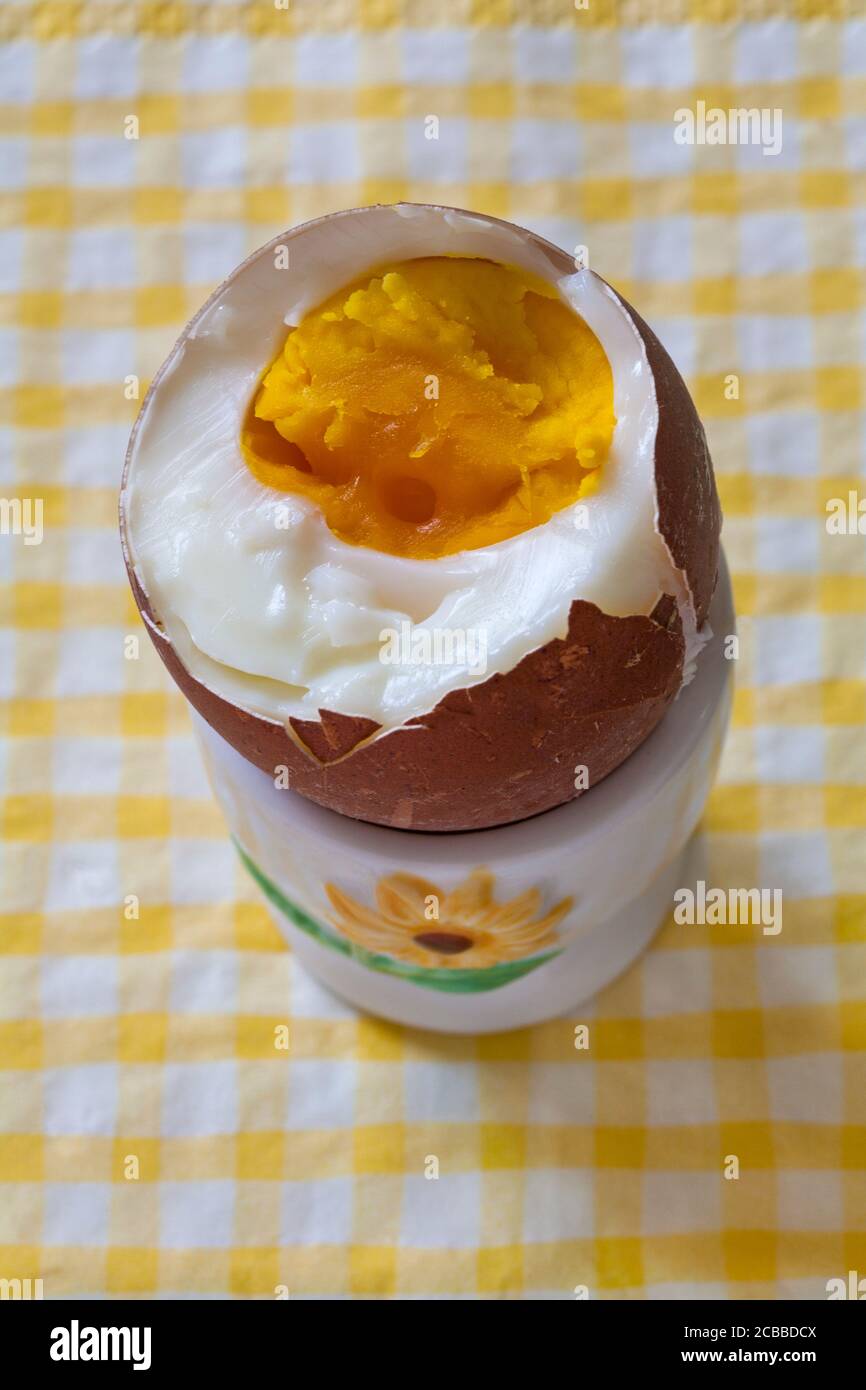 M&S British Farmed Free Range Maran Island Brown Egg in tazza di uovo su serviette di tovagliolo giallo e bianco controllato - uovo bollito con la parte superiore tagliata fuori per mostrare il tuorlo Foto Stock