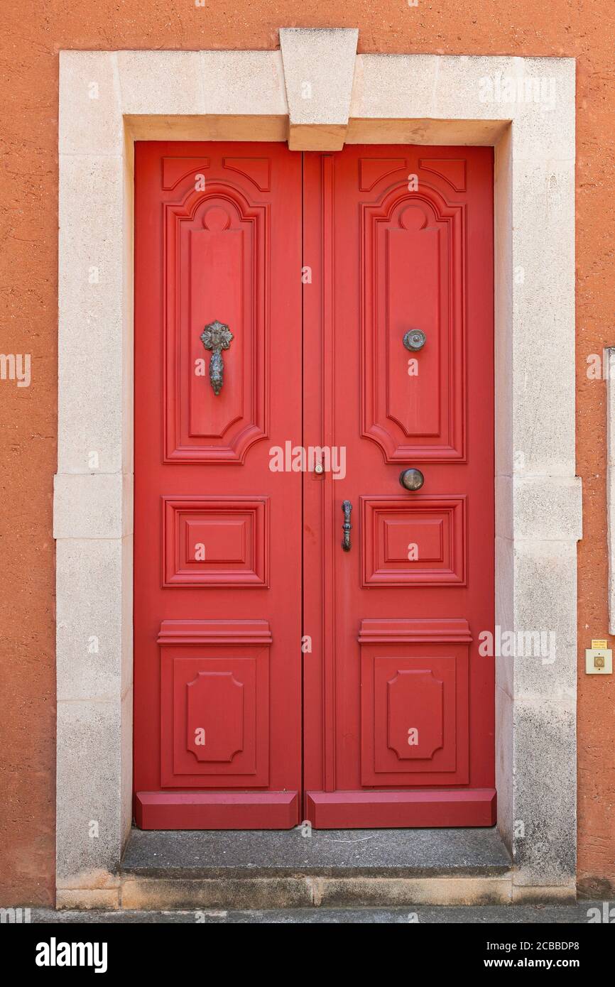 Una porta rossa nel villaggio di Roussillion, Luberon, Francia Foto Stock