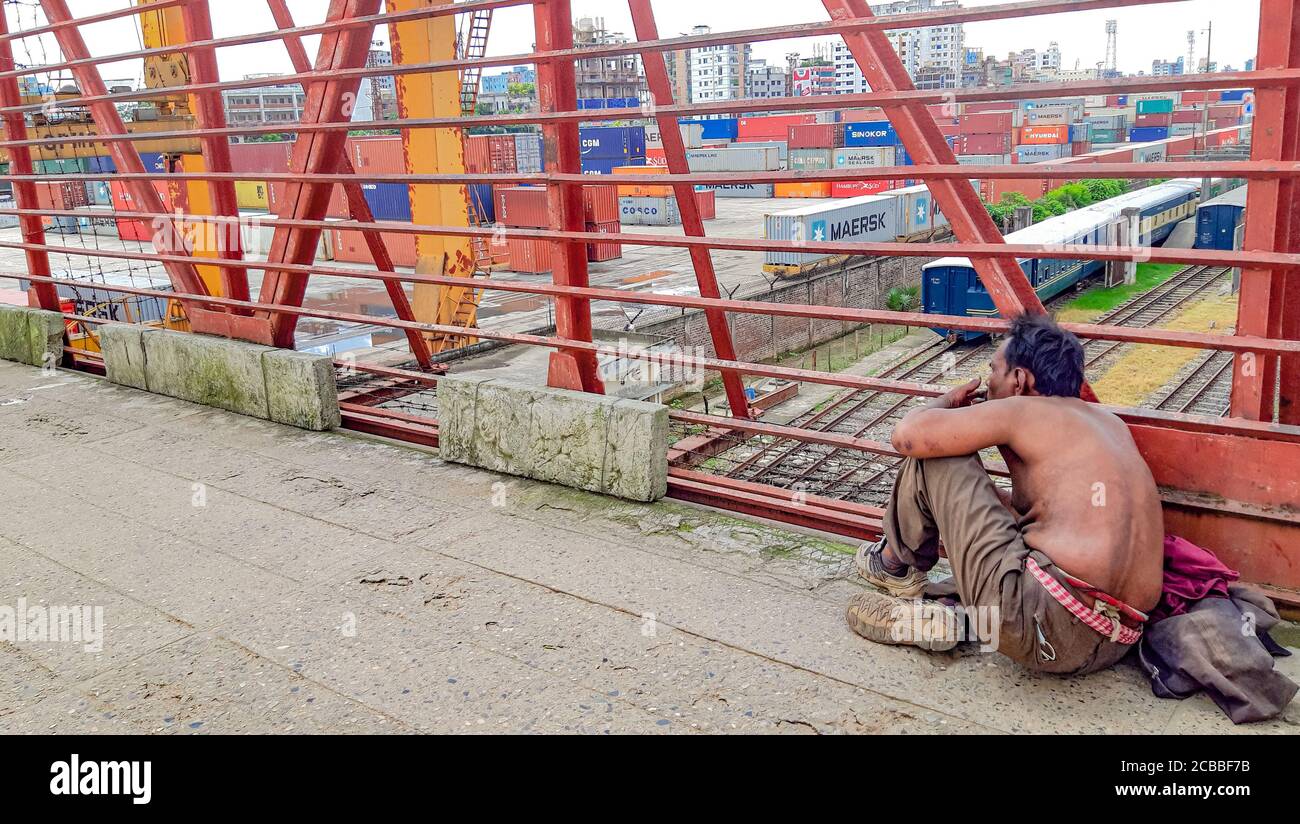 Senzatetto e uomo mentale seduto a piedi sul ponte. Foto Stock