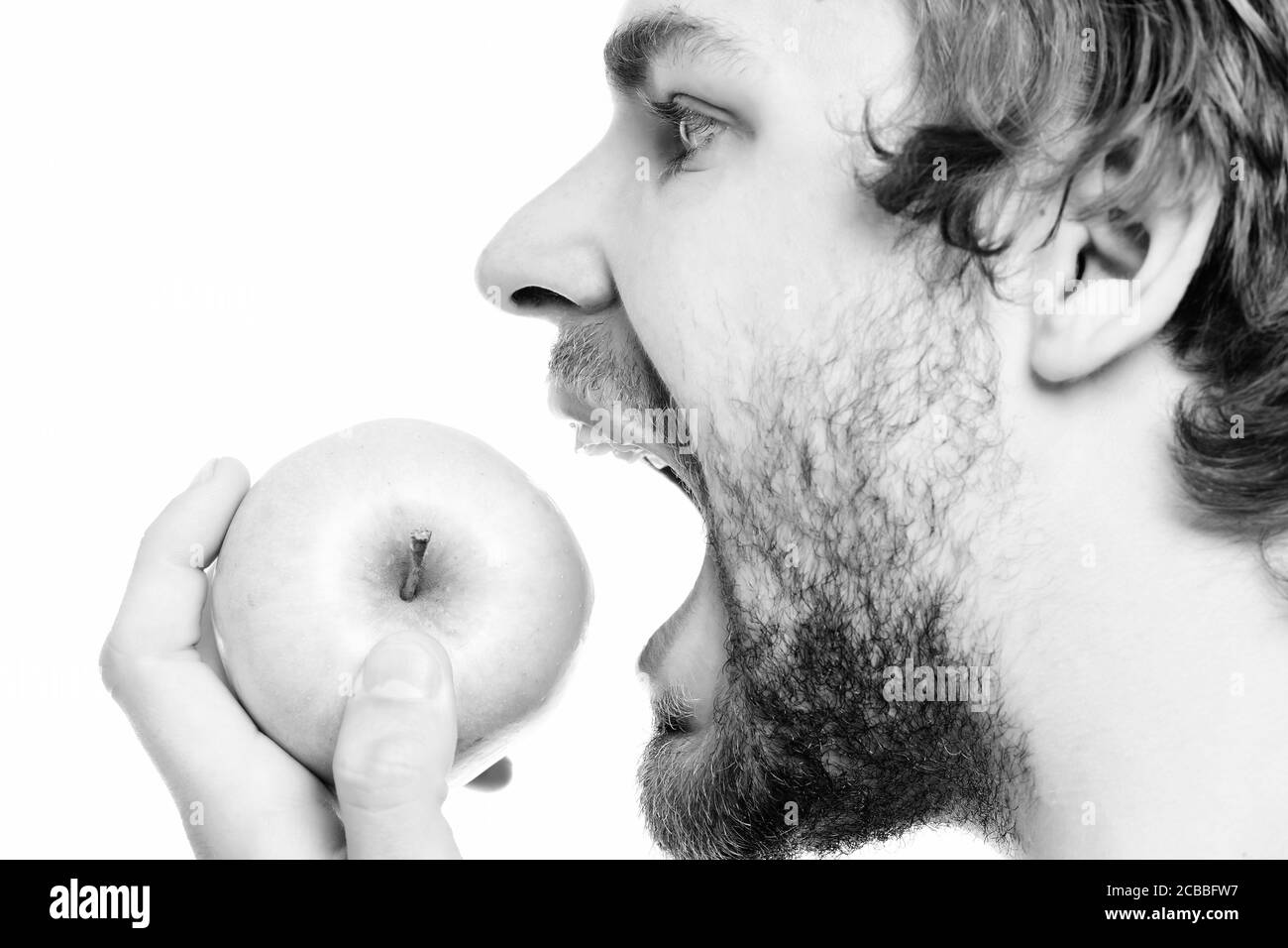 Apple e l'uomo. Giovane ragazzo caucasico mordere grande mela verde in stretta verso l'alto. Vista laterale, isolato su sfondo bianco Foto Stock