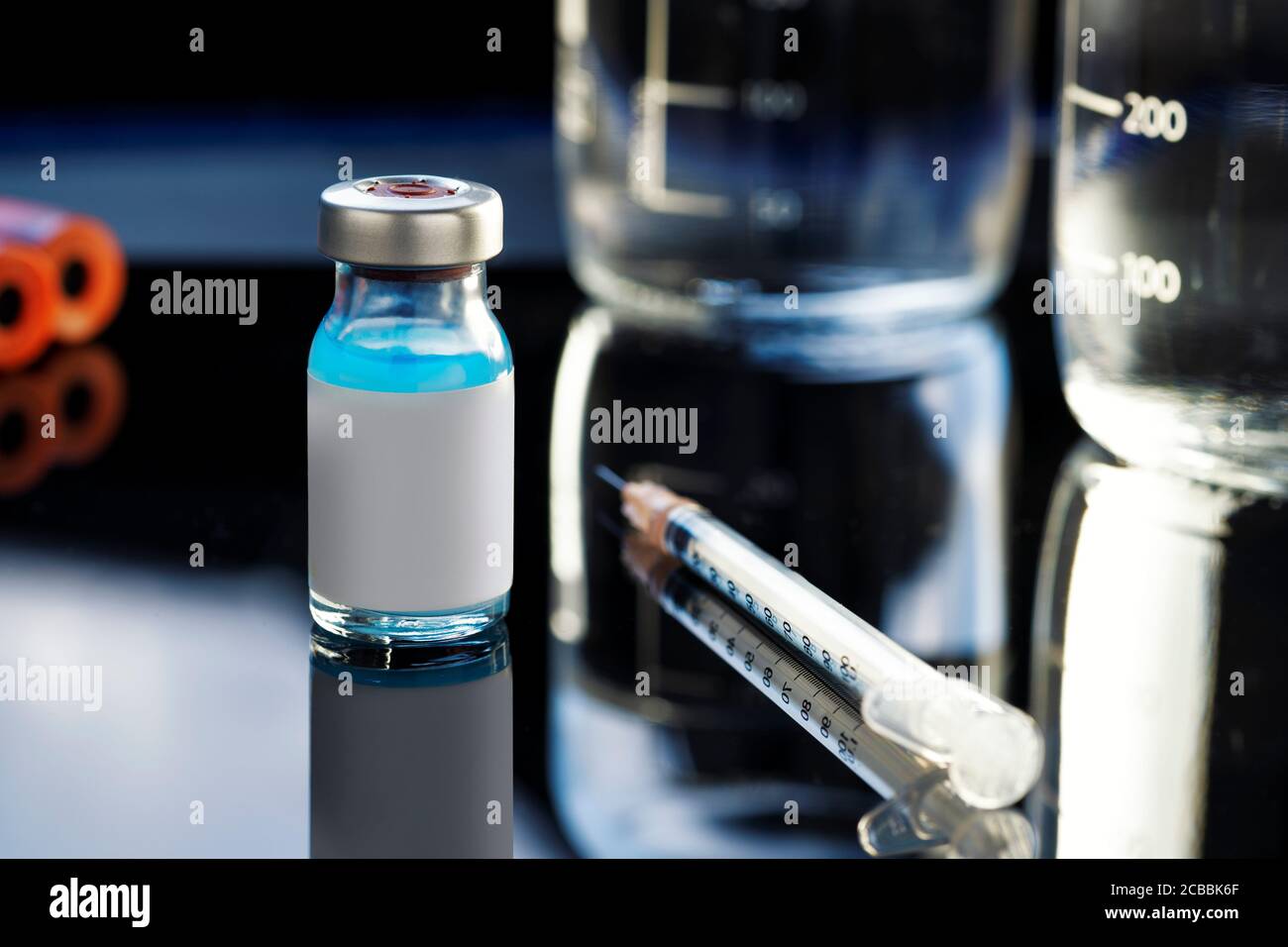 Flacone di vaccino con un liquido blu e una siringa su sfondo di laboratorio. Foto Stock