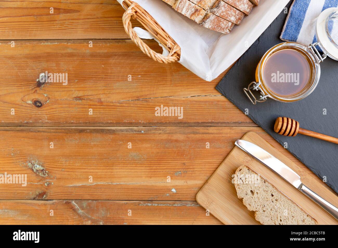 miele biologico e pane rustico su un vecchio tavolo di legno. Colazione sana. Foto Stock