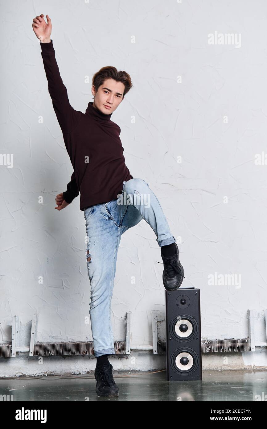 ballerino cool che mette la gamba sugli altoparlanti e posa alla telecamera. foto a tutta lunghezza. moda, sottocultura, arte Foto Stock