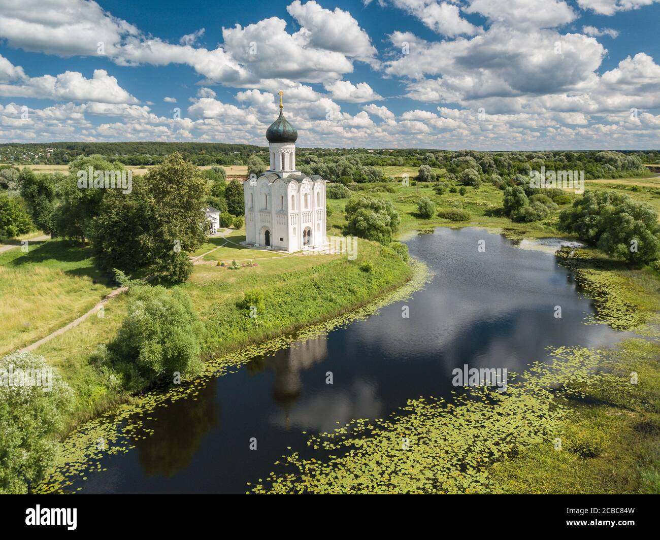 Grande veduta aerea panoramica dell'antica Chiesa dell'intercessione della Vergine Santa sul fiume Nervi nella soleggiata giornata estiva. Russia. Foto Stock