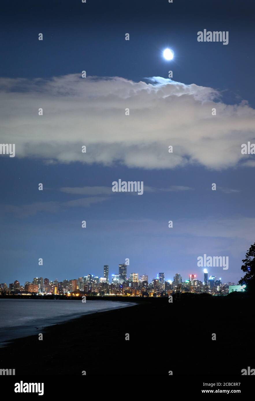 Città notte Vancouver Luna. La luna che sorge sullo skyline di Vancouver sulla English Bay. British Columbia, Canada. Foto Stock