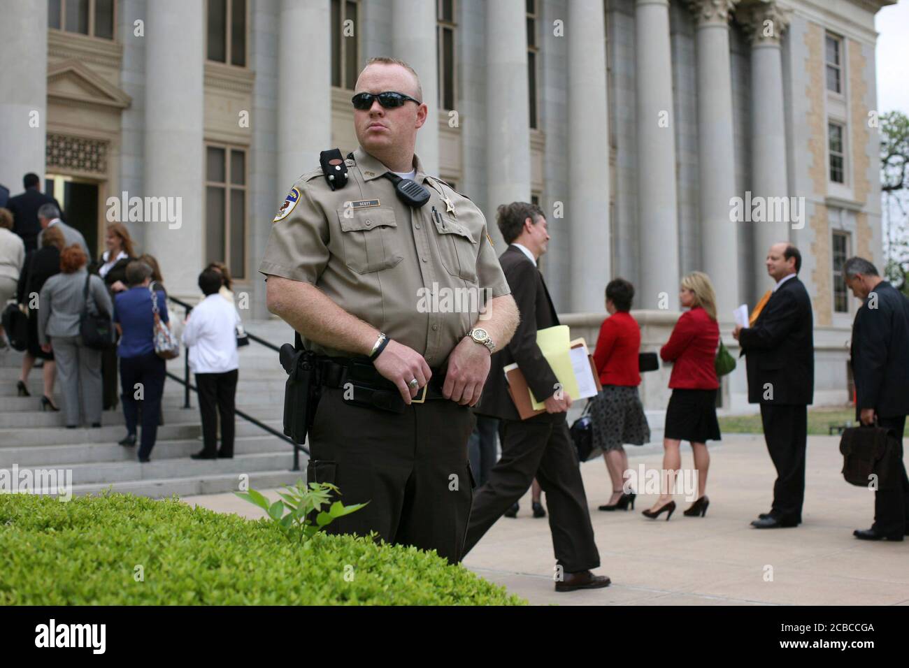 San Angelo, Texas USA, 17 aprile 2008: Il vice dello sceriffo della contea è in guardia come avvocati e altri si allineano per entrare nel tribunale della contea di Tom Green. Il tribunale è il luogo di un'udienza sulla custodia di centinaia di bambini presi dallo Stato del Texas dai loro genitori nel vicino complesso religioso desideroso di Zion. ©Bob Daemmrich Foto Stock