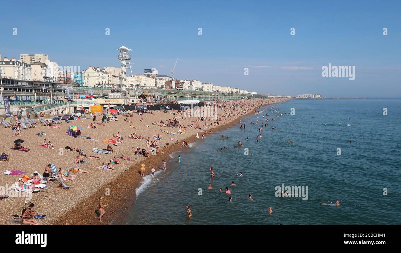 Brighton, UK - 10 agosto 2020: Un sacco di persone sulla spiaggia e in mare godendo il tempo caldo. Foto Stock