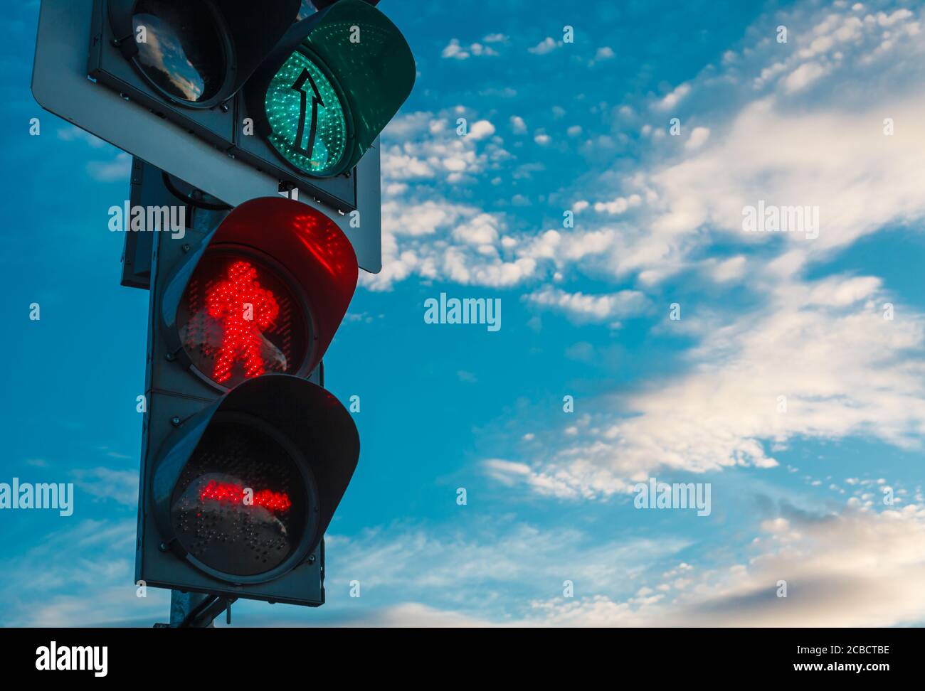 Semaforo con luce verde per auto e luce rossa per le persone. Luce di arresto contro il cielo blu con nuvole bianche Foto Stock