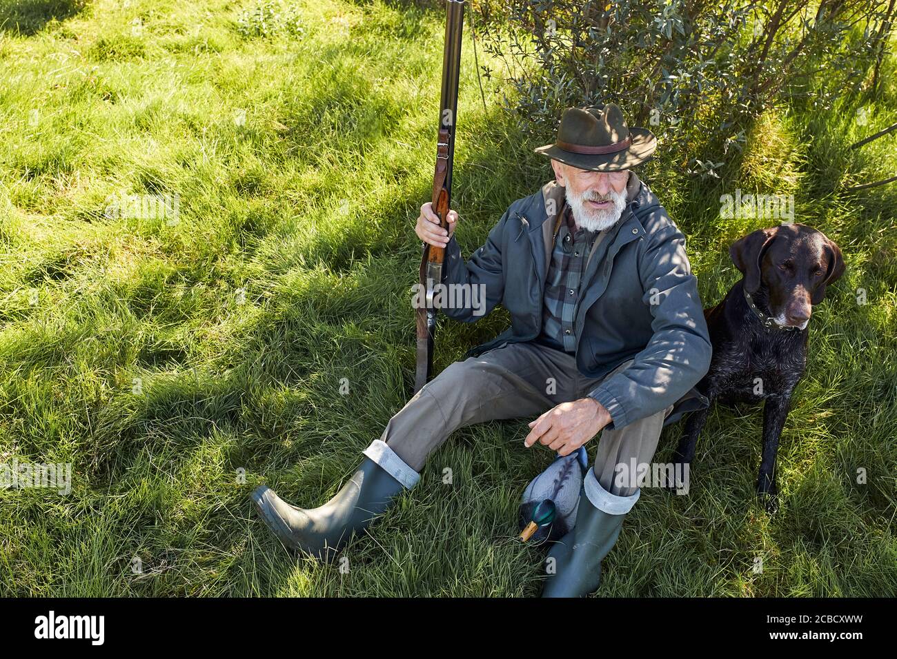 Ricerca trofeo con cane. Uomo anziano pronto a cacciare. Siediti riposando prima di andare a caccia Foto Stock