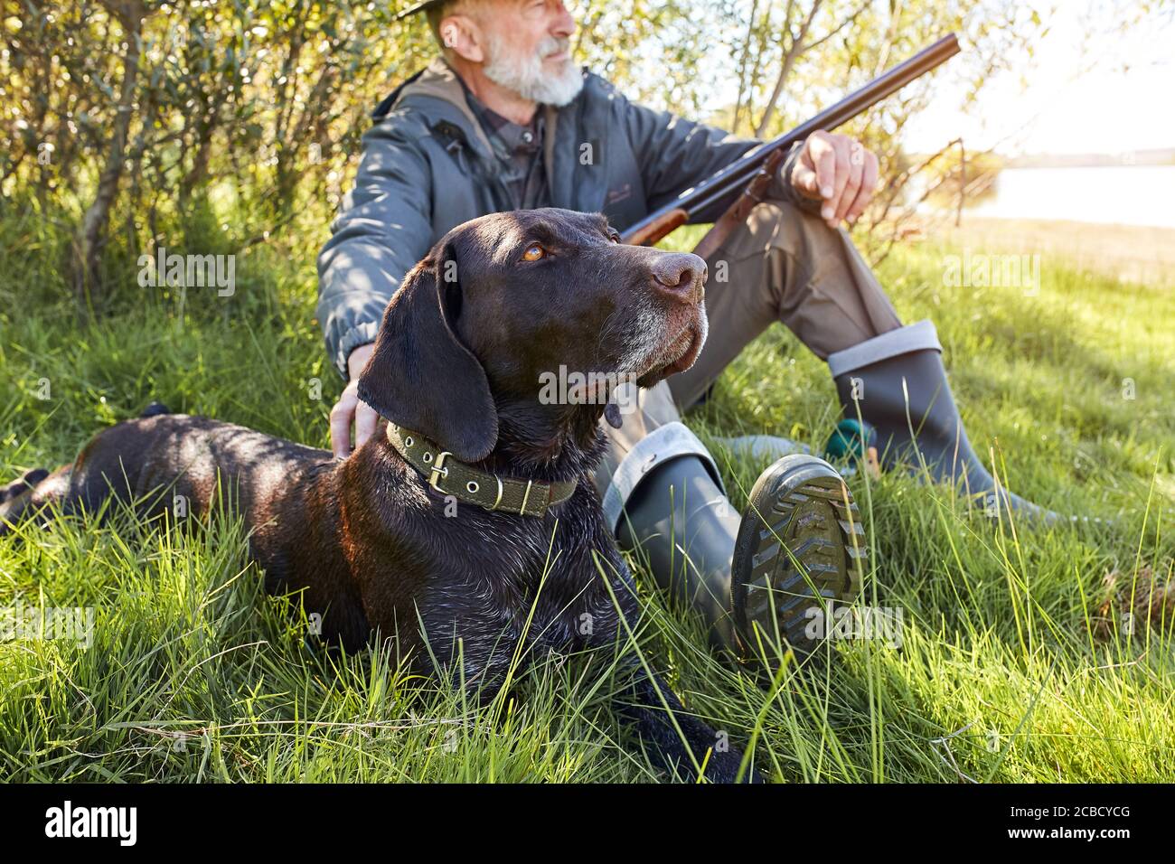 Ricerca trofeo con cane. Uomo anziano pronto a cacciare. Siediti riposando prima di andare a caccia Foto Stock