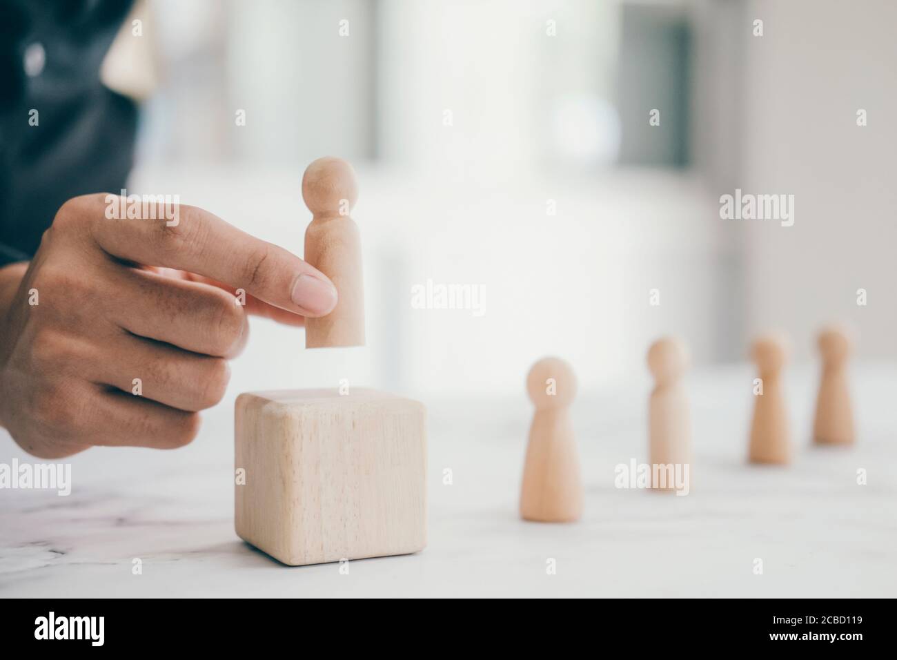 concetto aziendale di team leader di successo e risorse umane. uomo d'affari sceglie a mano la bambola umana di legno tra molti cadidati e diversi. Foto Stock